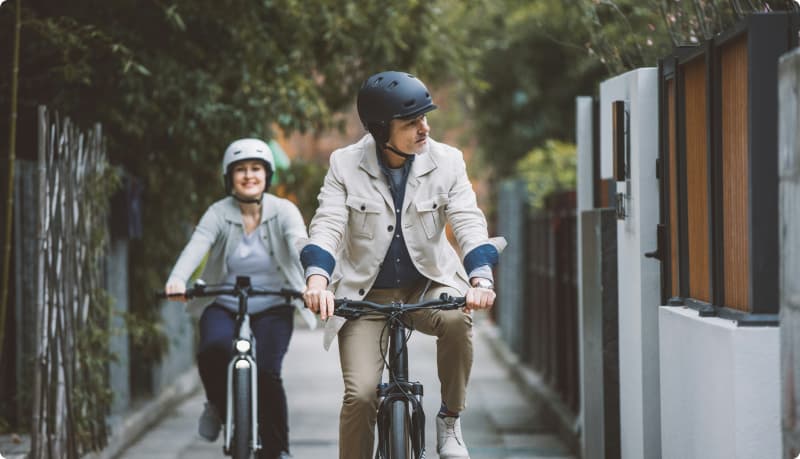 Mies ja nainen ajavat pyörillä kaupungissa.