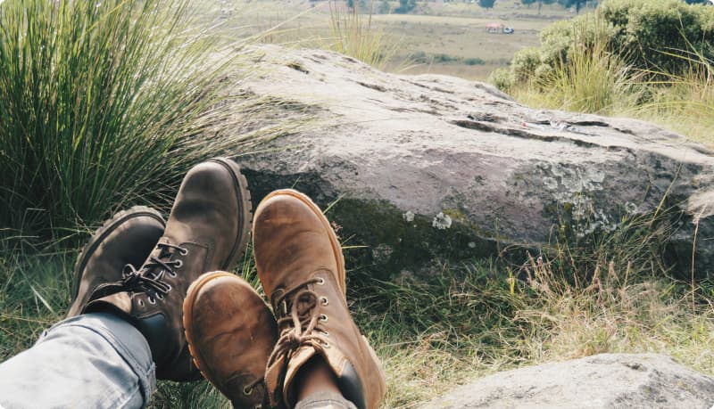 Kahden ihmisen kengät niittymaista horisonttia vasten.
